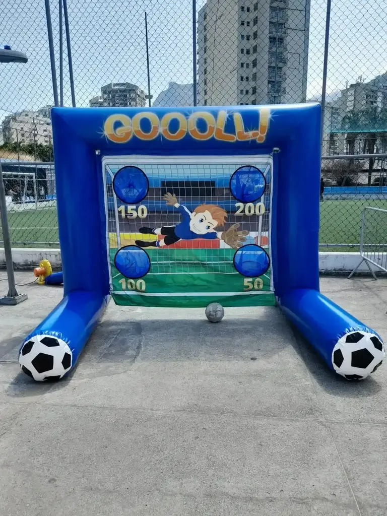 Foto de um chute a gol inflável com o design de uma trave de futebol e buracos com pontuações diferentes para testar a precisão, um item popular na locação de brinquedos infláveis.