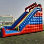 Foto de um tobogã inflável gigante com rampa de descida alta e cores vibrantes, um dos principais brinquedos para aluguel em festas de grande porte.