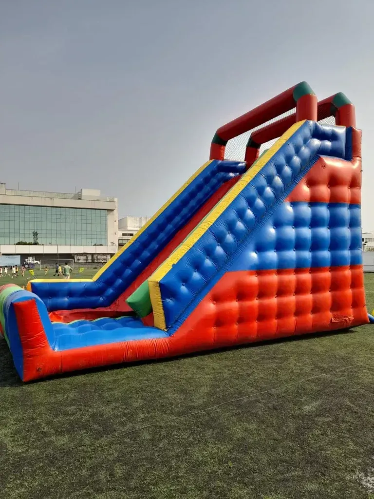 Foto de um tobogã inflável gigante com rampa de descida alta e cores vibrantes, um dos principais brinquedos para aluguel em festas de grande porte.